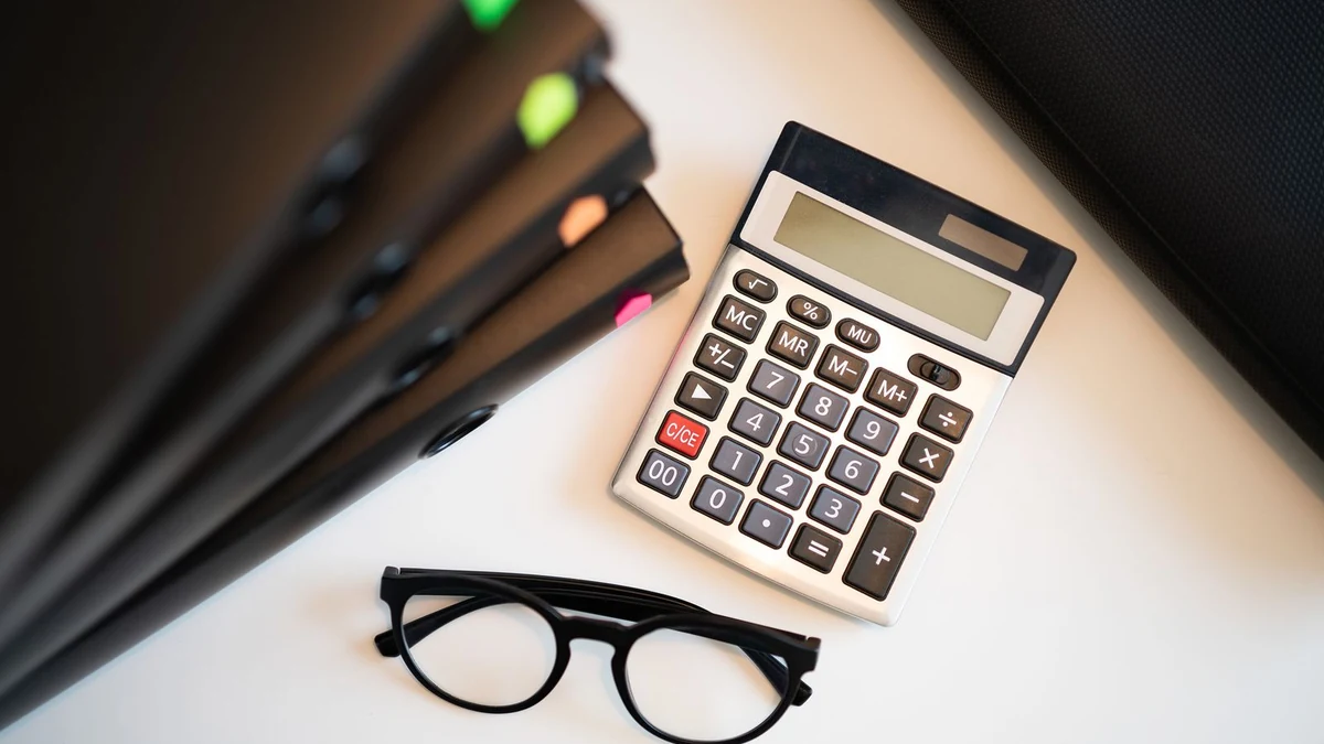A calculator, business files and a pair of glasses on a desk